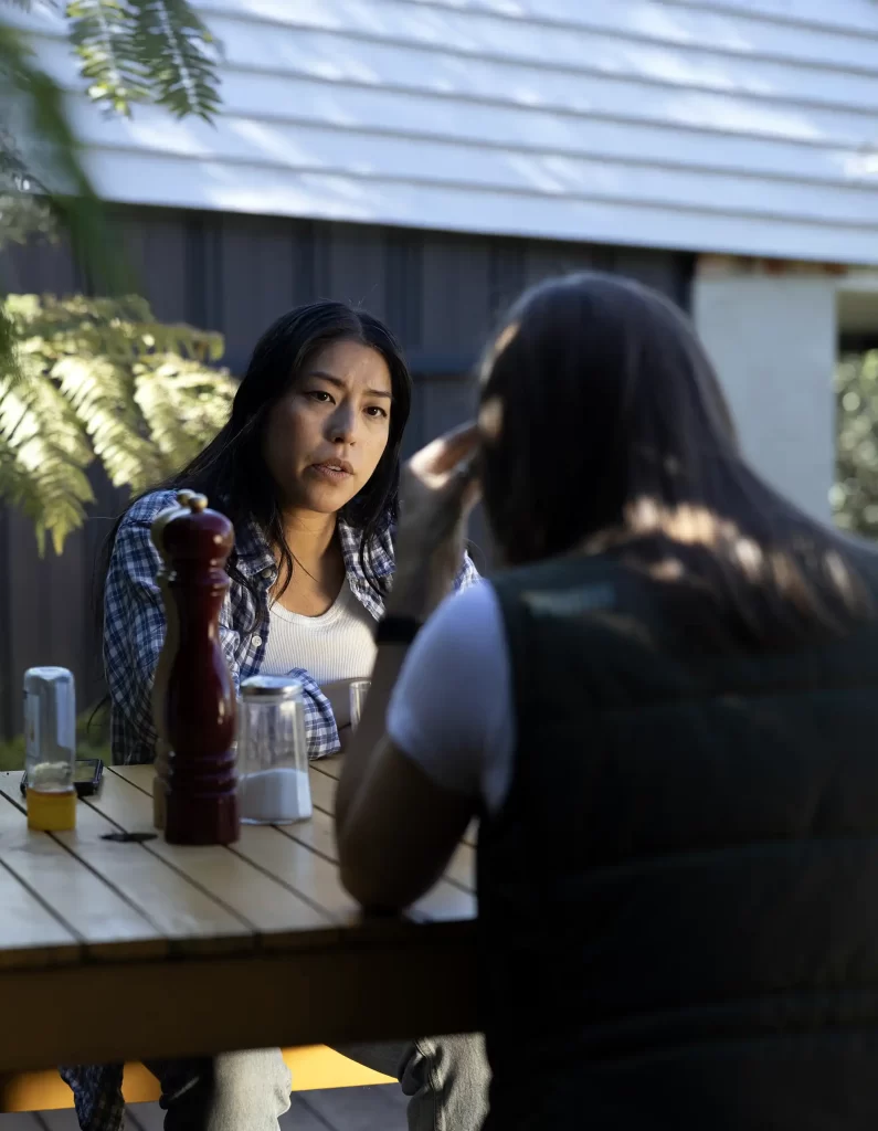 A concerned friend looking at an upset woman. Both are sitting outside at a restaurant.